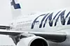 Close-up of a Finnair passenger jet fuselage and engine on an airport apron.