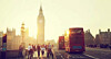 Big Ben and a red London bus on a busy Westminster street at sunset.