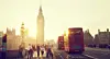 Big Ben and a red London bus on a busy Westminster street at sunset.