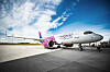 Wizz Air Airbus aircraft parked on an airport apron under a partly cloudy sky.