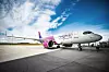 Wizz Air Airbus aircraft parked on an airport apron under a partly cloudy sky.