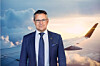 Fredrik Kämpfe standing in front of an aircraft wing against a cloudy sunset sky.