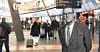 Resenärer med rullväskor går genom en ljus flygplatsterminal.