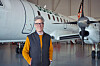 En man står framför ett mindre passagerarflygplan i en hangar.