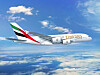 Emirates passenger jet flying above clouds against a blue sky.