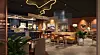 Digital rendering av en hotellobby med bar, soffor, bord och växter i varm belysning.