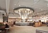 Contemporary hotel lobby with chandelier, marble desk and seating area.