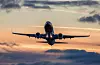 A Norwegian plane takes off against a colourful sunset sky.