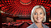 Portrait of a smiling woman in front of a red-lit venue with tables and chairs.