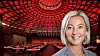 Portrait of a smiling woman in front of a red-lit venue with tables and chairs.