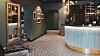 Hotel reception area with patterned floor, curved blue desk, dark walls and warm pendant lighting.