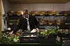 Worker arranging fresh vegetables in crates inside a produce storage area.