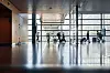 Travellers sit and walk through the bright glass-walled interior of Stockholm Arlanda Airport.