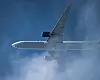 Passagerarflygplan sett underifrån när det flyger genom blågrå moln.