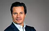 Portrait of Mathias Hedlund, chief executive of Etraveli Group, wearing a navy jacket against a grey background.