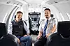 Markus Olsson and Mattias Eriksson seated inside a bright private aircraft cabin.