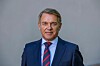 Portræt af Hallvard Bratberg i mørkt jakkesæt og slips foran en grå baggrund.