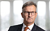 Porträtt av Erik Thedéen i mörk kostym och glasögon framför ljusa fönster.