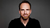 Studio portrait of Visita chief executive Christer Fogelmarck wearing a black shirt against a grey background.