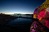 Colourful projections light a rocky shore beside dark water at Smögen Art Light Festival.
