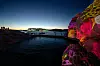 Colourful projections light a rocky shore beside dark water at Smögen Art Light Festival.