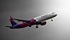 Ett Wizz Air-passagerarflygplan flyger genom luften mot en grå bakgrund.