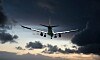 Passagerarflygplan sett framifrån i luften mot mörka moln och en ljus kvällshimmel.