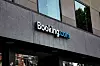 Booking.com-logotyp på fasaden till en modern kontorsbyggnad.