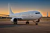 Ett vitt Boeing-passagerarflygplan står på en flygplatsplatta i varmt kvällsljus.