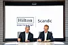 Chris Nassetta and Jens Mathiesen sign documents beneath Hilton and Scandic logos.