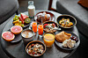 Uppdukad hotellfrukost med kaffe, juice, frukt, bröd och flera maträtter på ett runt bord.