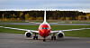 Ett rödvitt Norwegianflygplan står framifrån på en asfalterad flygplatsyta.
